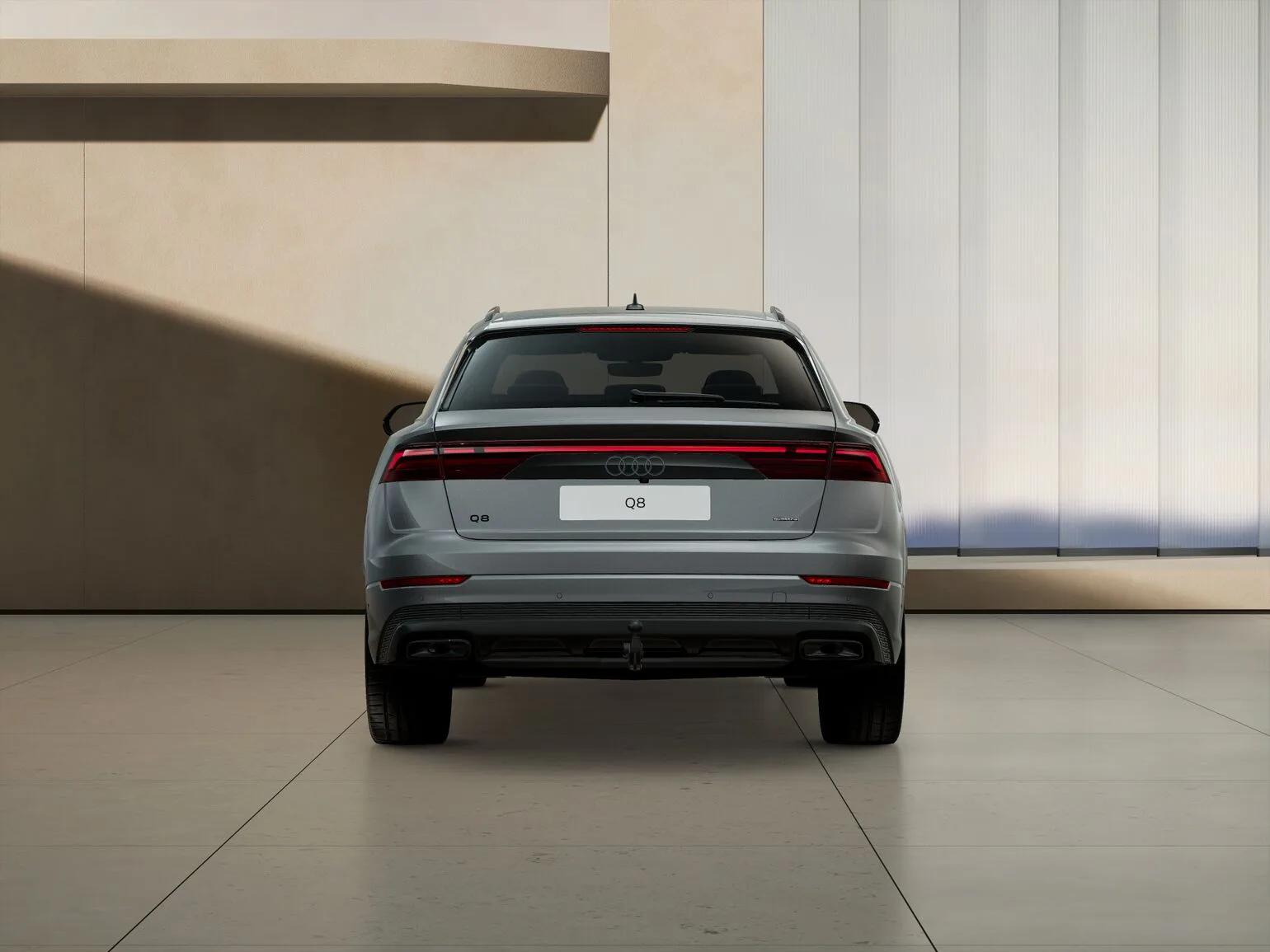 Szare Audi Q8 TDI quattro tiptronic 2026 z tyłu, centralne ujęcie, w jasnym nowoczesnym wnętrzu showroomu