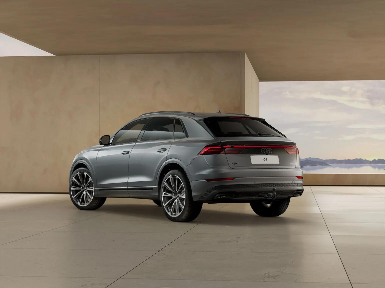Szare Audi Q8 TDI quattro tiptronic 2026, ujęcie z tyłu pod kątem, w nowoczesnym jasnym wnętrzu na dużych felgach