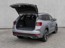 Srebrna Škoda Kodiaq RS z otwartą klapą bagażnika, widok z tyłu pod kątem, pokazana przestrzeń bagażowa