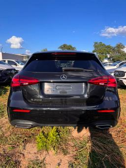 Tył czarnego Mercedesa A 200 Hatchback AMG z emblematem modelu i podwójnymi końcówkami wydechu na placu дилerskim
