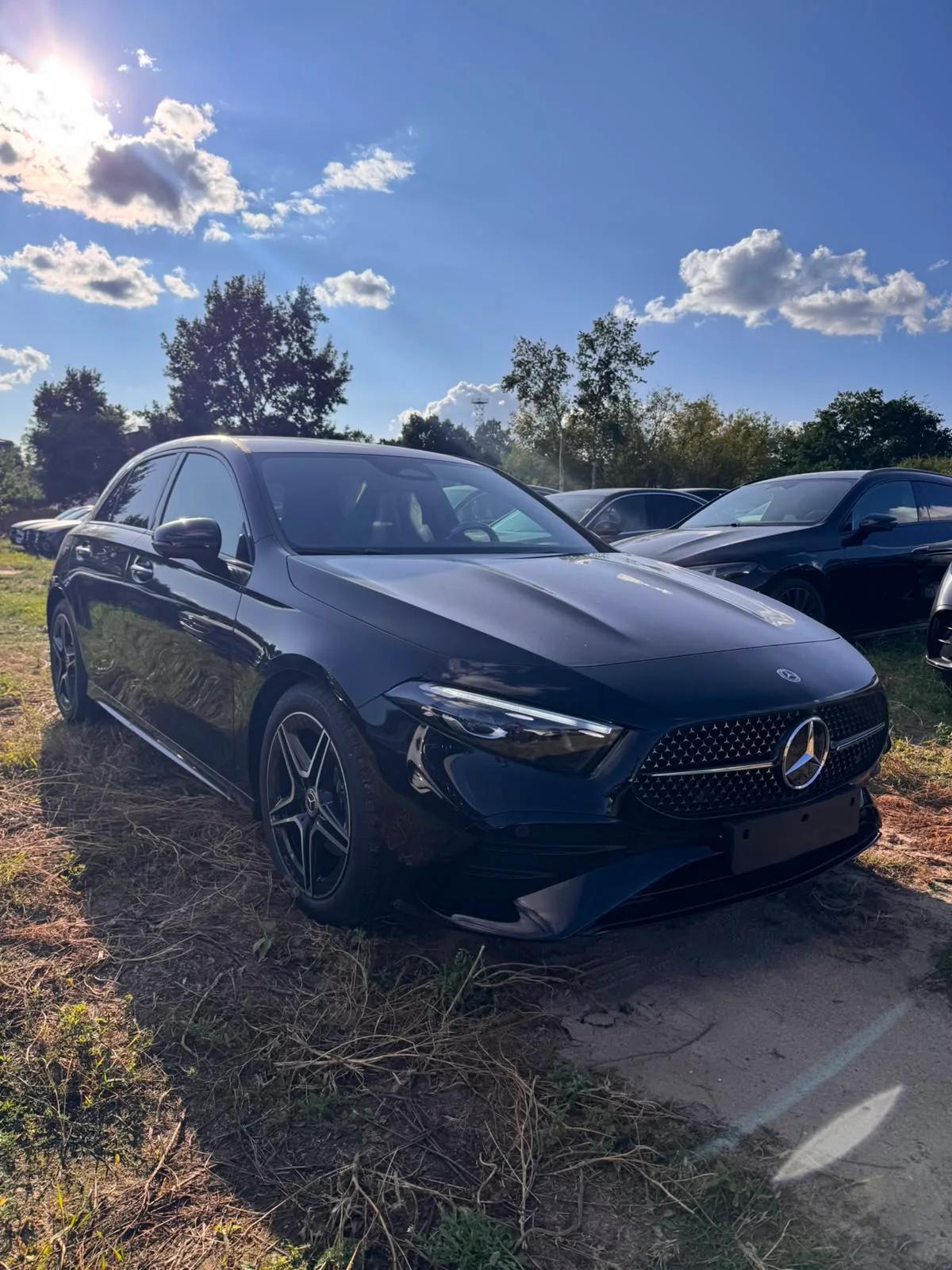 Czarny Mercedes-Benz A 200 Hatchback AMG, ujęcie z przodu pod kątem na tle drzew i innych samochodów