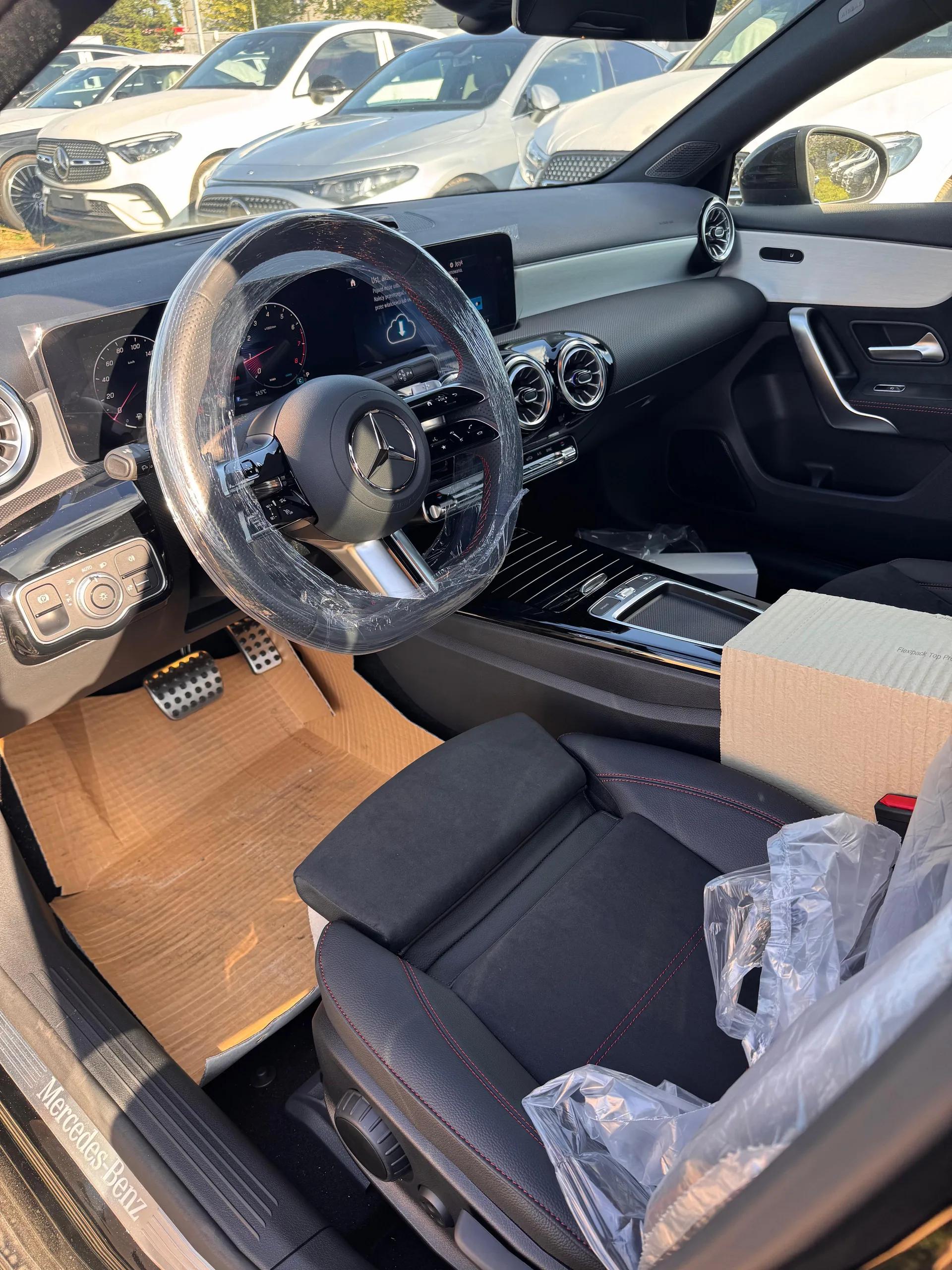 Wnętrze Mercedesa klasy A 200 AMG z kierownicą, cyfrowymi zegarami i sportowymi fotelami obszytymi czerwoną nicią