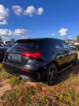 Czarny Mercedes-Benz A 200 hatchback AMG, widok z tyłu i boku na tle salonu samochodowego