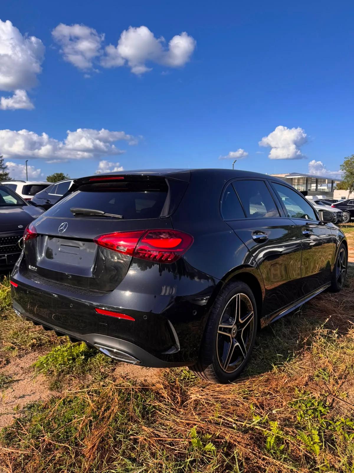 Czarny Mercedes-Benz A 200 hatchback AMG, widok z tyłu i boku na tle salonu samochodowego