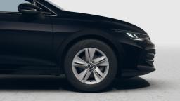 Zbliżenie przedniego koła i reflektora ciemnego Volkswagena Golfa Varianta na jasnym tle